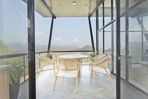 A balcony with a round table and wicker chairs, overlooking a mountainous landscape. - Walaa Kulu – A Villa by 98 Acres (Ella)