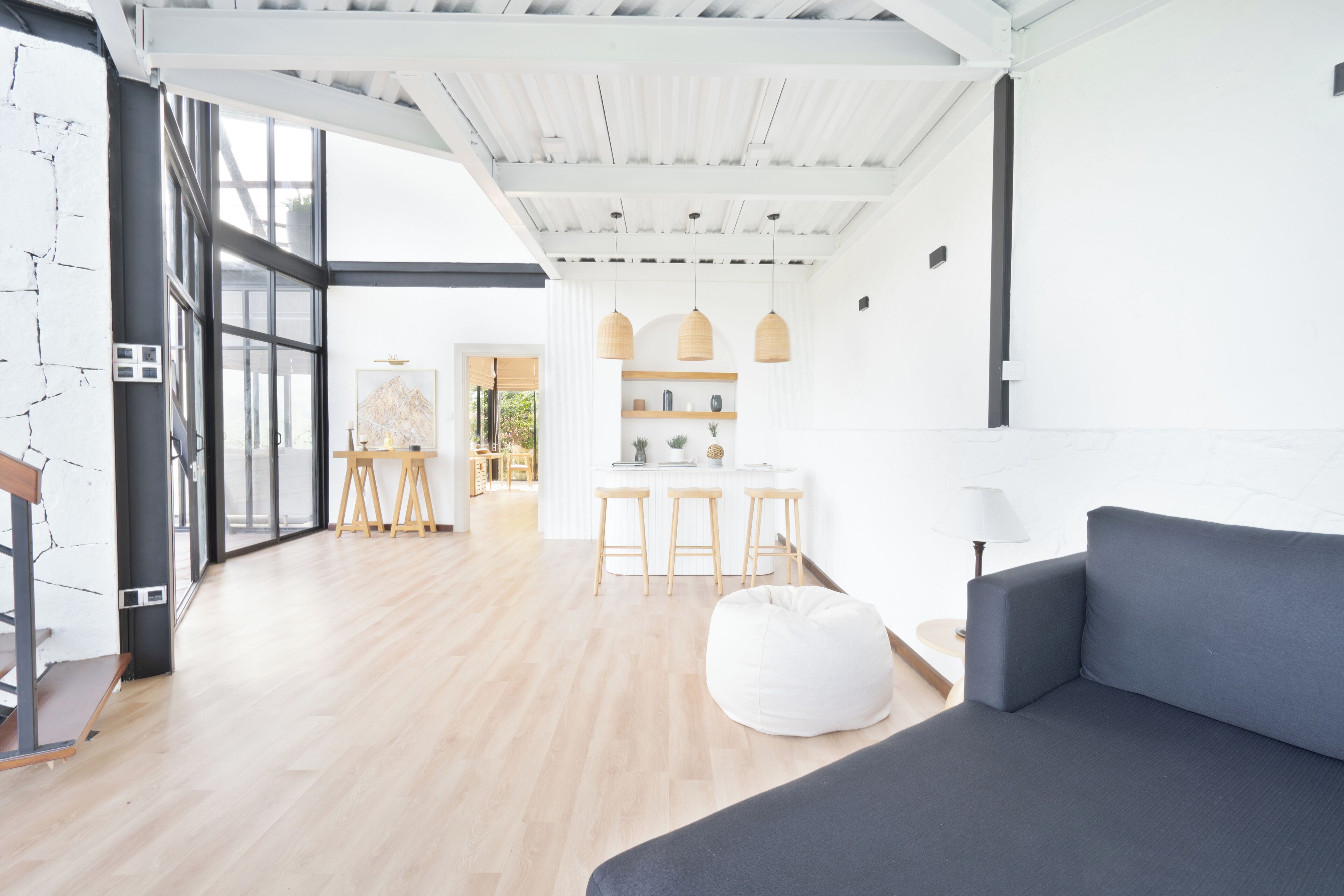 Een modern interieur met een grijze bank, houten vloeren en een keuken met barkrukken.