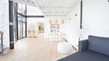 Een modern interieur met een grijze bank, houten vloeren en een keuken met barkrukken.