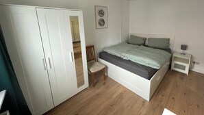 A bedroom with a bed, a nightstand, a chair, and a wardrobe. - Ferienwohnung in Fehrenbach (Masserberg)