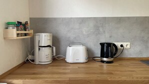 A kitchen with a coffee maker, toaster, and kettle on the counter. - Ferienwohnung in Fehrenbach (Masserberg)