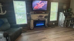 A living room with a fireplace, a television mounted above it, and a couch.