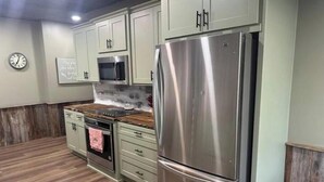A kitchen with stainless steel appliances, wooden flooring, and light green cabinets.