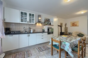 Une cuisine moderne avec des armoires blanches, un four encastré et un coin repas avec une table mise pour deux personnes.