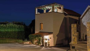 A two-story building with a balcony, a stone wall, and a well-lit entrance. - House Rea is ideal for a retreat in nature, close to the richness of Istria ! (buzet)