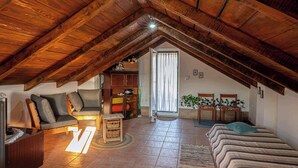 An attic bedroom with a sloped wooden ceiling, a sofa, a bed, a small table, and a cabinet. - House Rea is ideal for a retreat in nature, close to the richness of Istria ! (buzet)