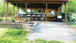 A covered outdoor area with a wooden structure, a grill, and a camper parked behind it. - Private one-of-a-kind Camping experience! Hot Tub! (Narvon)