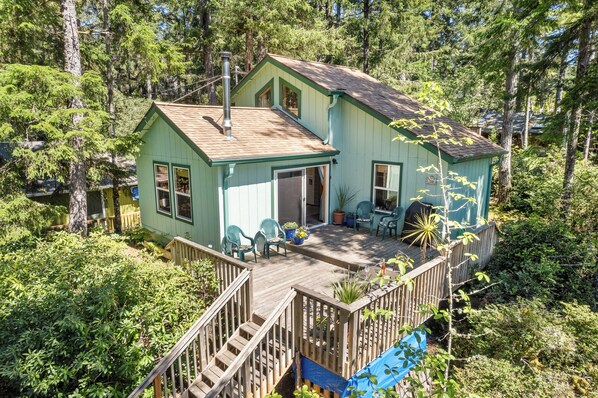 A two-story house with a deck, surrounded by dense forest. - Quiet Area, Perfect Couples Retreat Nestled in the Trees, Large Deck (Manzanita)