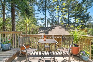 A wooden deck with a table and chairs, surrounded by potted plants and trees. - Quiet Area, Perfect Couples Retreat Nestled in the Trees, Large Deck (Manzanita)