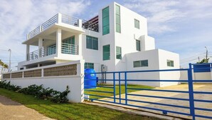 Ein modernes, zweistöckiges Gebäude mit weißer Fassade, einem blauen Tor und einem großen Wassertank.
