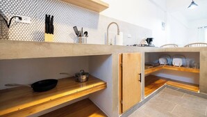 Eine moderne Küche mit Holzregalen, einer Spüle und einer gefliesten Rückwand.