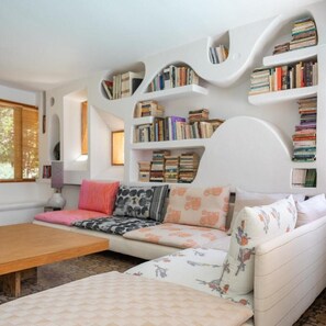 A cozy living room with a sofa, a wooden coffee table, and bookshelves filled with books.