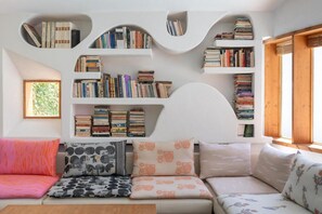 Ein gemütliches Wohnzimmer mit einer eingebauten Bücherreolen, einem bequemen Sofa und einem Fenster mit Holzläden.