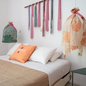 Ein Schlafzimmer mit Bett, Kissen, einer aufhängbaren Tasche und einem Wandhaken für Krawatten.