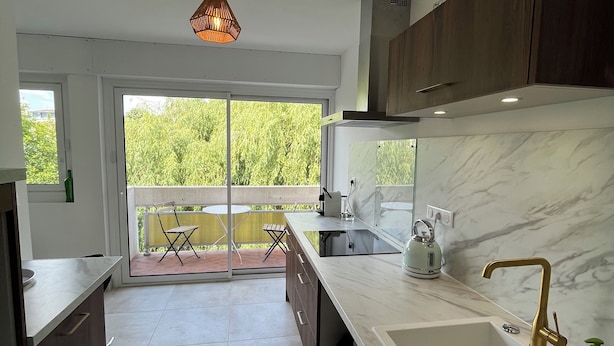 A modern kitchen with a large sink, dark wooden cabinets, and a view to a balcony. - Balcon sur la Rivière Face à la Vieille Ville (Périgueux)