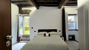 A bedroom with a bed, a window, a radiator, and a stone wall. - Secret Garden Suite- Bluchalet  (Riomaggiore)