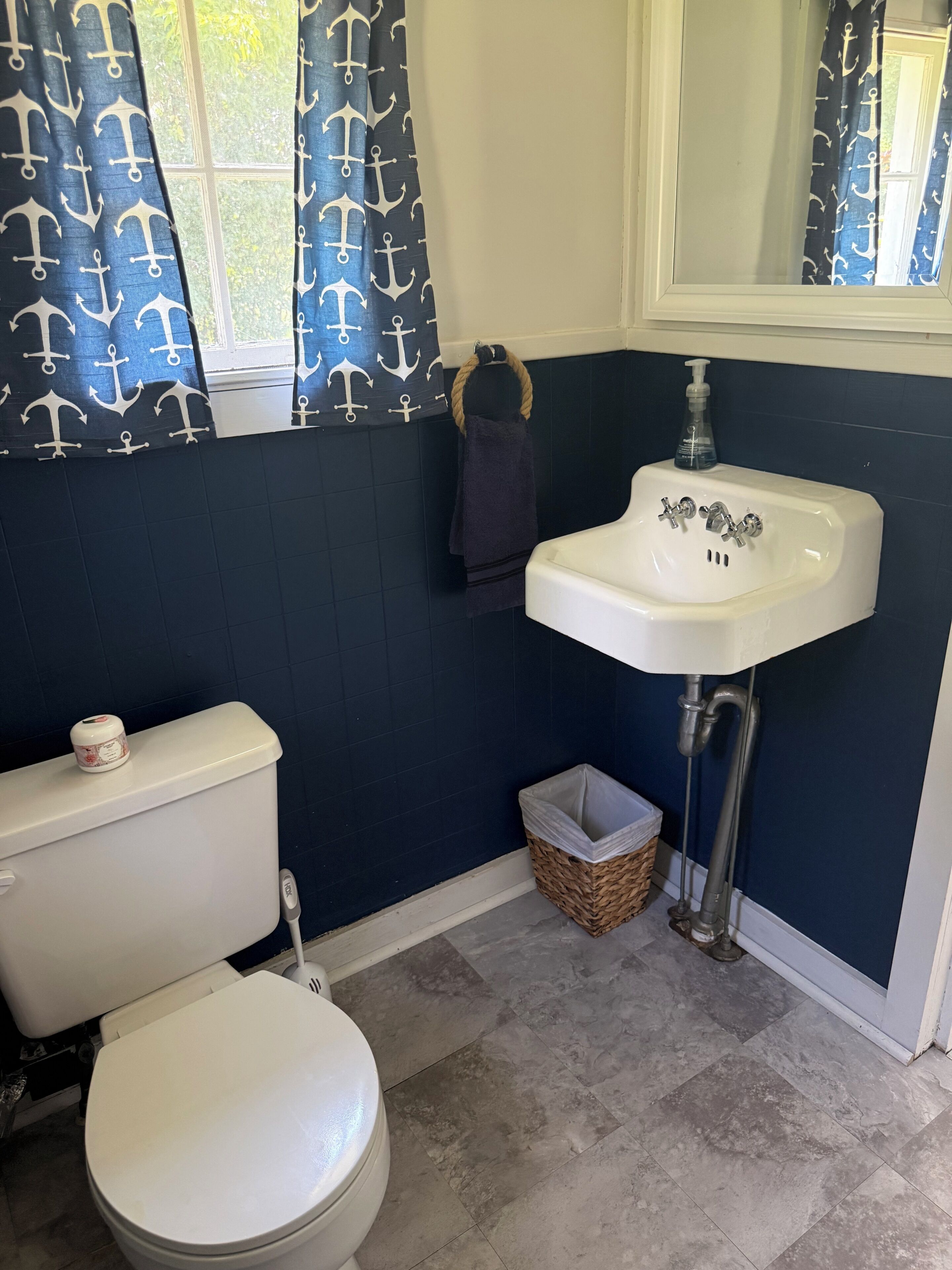 Ein Badezimmer mit Toilette, Waschbecken und einem Fenster mit Vorhängen.