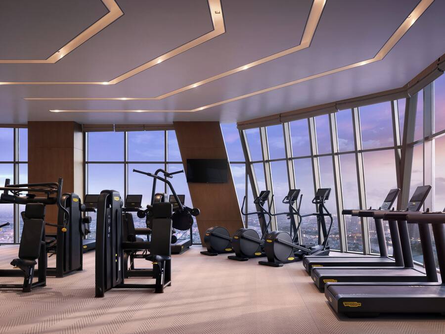 Ein modernes Fitnessstudio mit diversen Trainingsgeräten, großen Fenstern und Stadtblick sowie einer großzügigen Gestaltung.
