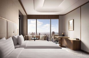 Una habitación de hotel moderna con una cama grande, un escritorio y vistas a la ciudad.