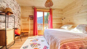 A cozy wooden cabin bedroom with a bed, a desk, and a chair. - 🏡☀️ Chez Lily – Family House at the Foot of Le Criou 🌱⛰ (Samoëns)