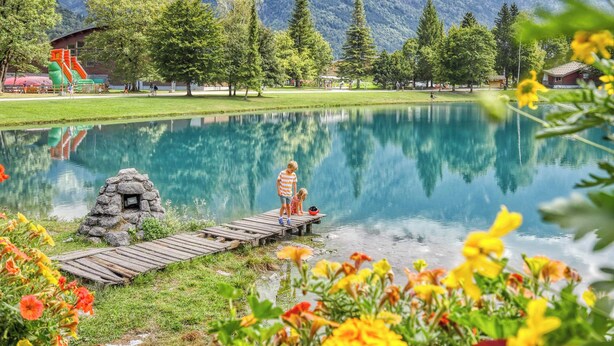 A serene lakeside scene with a wooden dock, a stone structure, and a mountain backdrop. - 🏡☀️ Chez Lily – Family House at the Foot of Le Criou 🌱⛰ (Samoëns)