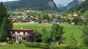 A rural village with traditional wooden houses, surrounded by lush green fields and mountains. - 🏡☀️ Chez Lily – Family House at the Foot of Le Criou 🌱⛰ (Samoëns)