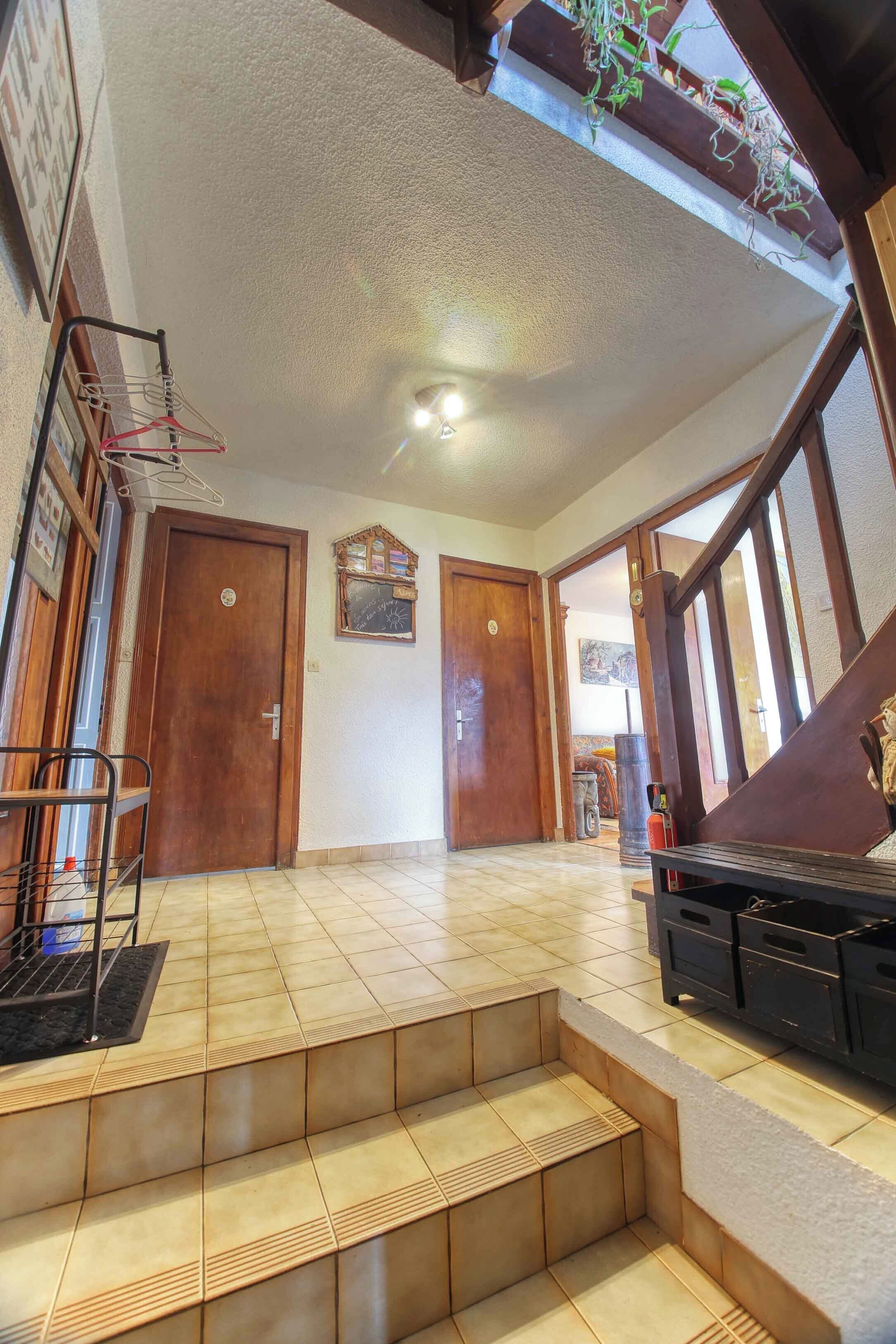 A spacious hallway with wooden doors, a staircase, and a seating area with a bench.