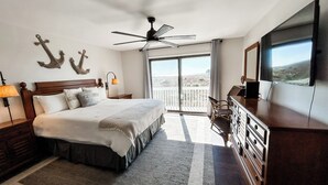 Een slaapkamer met een bed, een plafondventilator, een dressoir, een televisie en uitzicht op de omgeving.
