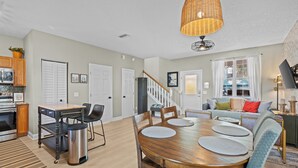A spacious kitchen with modern appliances, a dining area with a wooden table and chairs, and a living room with a sofa and a TV. - Southern Charmer|Private Backyard|Walk to Downtown (Saint Augustine)