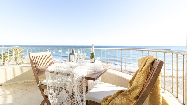 A balcony with a table set for two, a bottle of champagne, and a chair with a blanket. - Breathe, 100% Mediterranean. Mandala apARTments (Calafell)