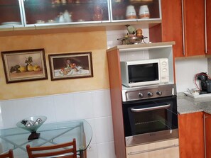 A kitchen with a microwave, oven, and a glass table with chairs. - A luxury apartment in the center of Calafell (Calafell)