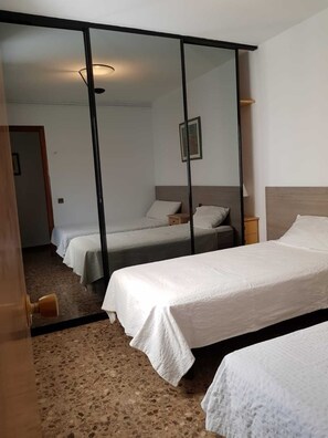 Ett hotellrum med två sängar, en stor spegel och ett trägolv.