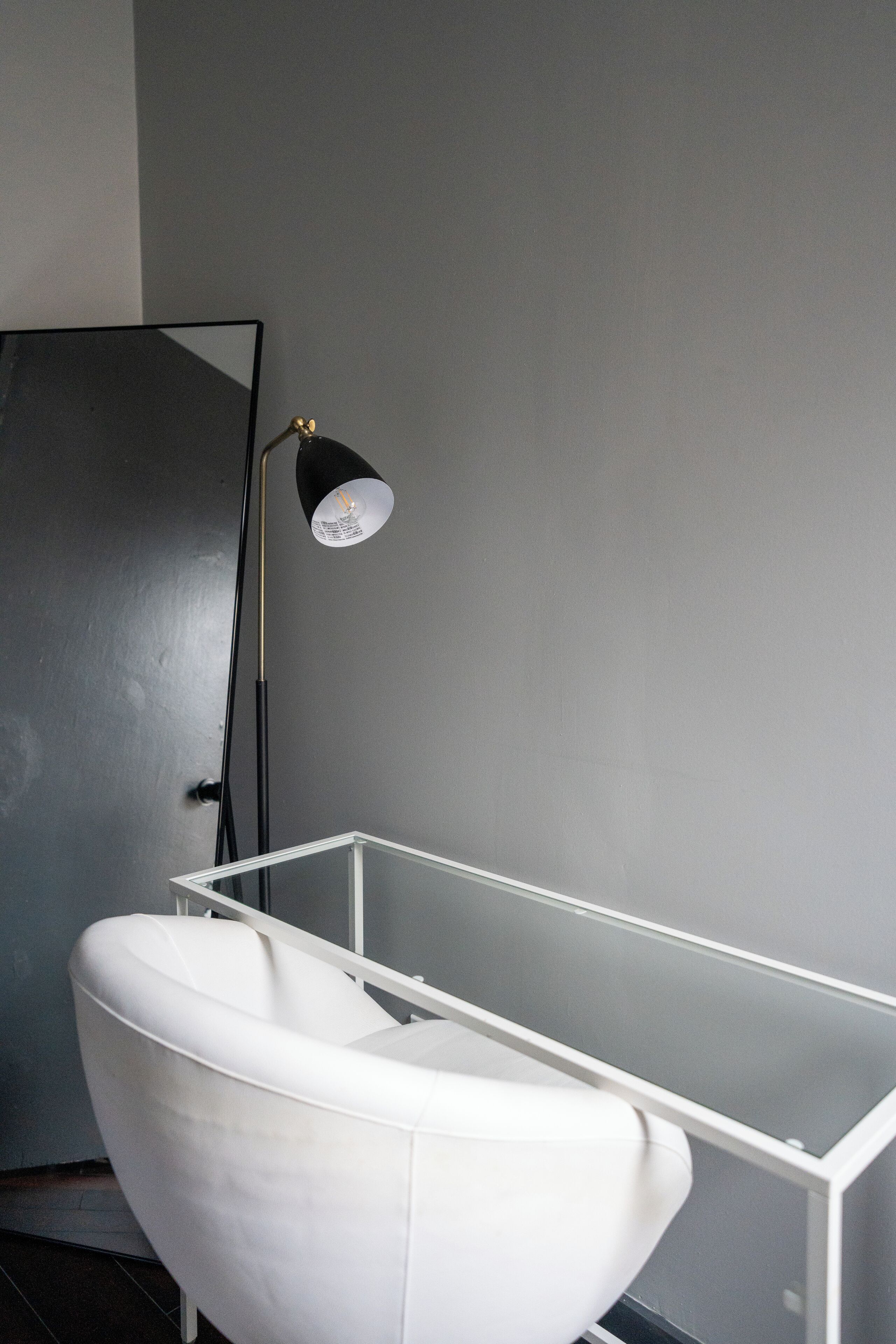 Ein modernes Badezimmer mit einer weißen Badewanne, einer schwarzen Stehlampe und einer Duschkabine aus Glas.
