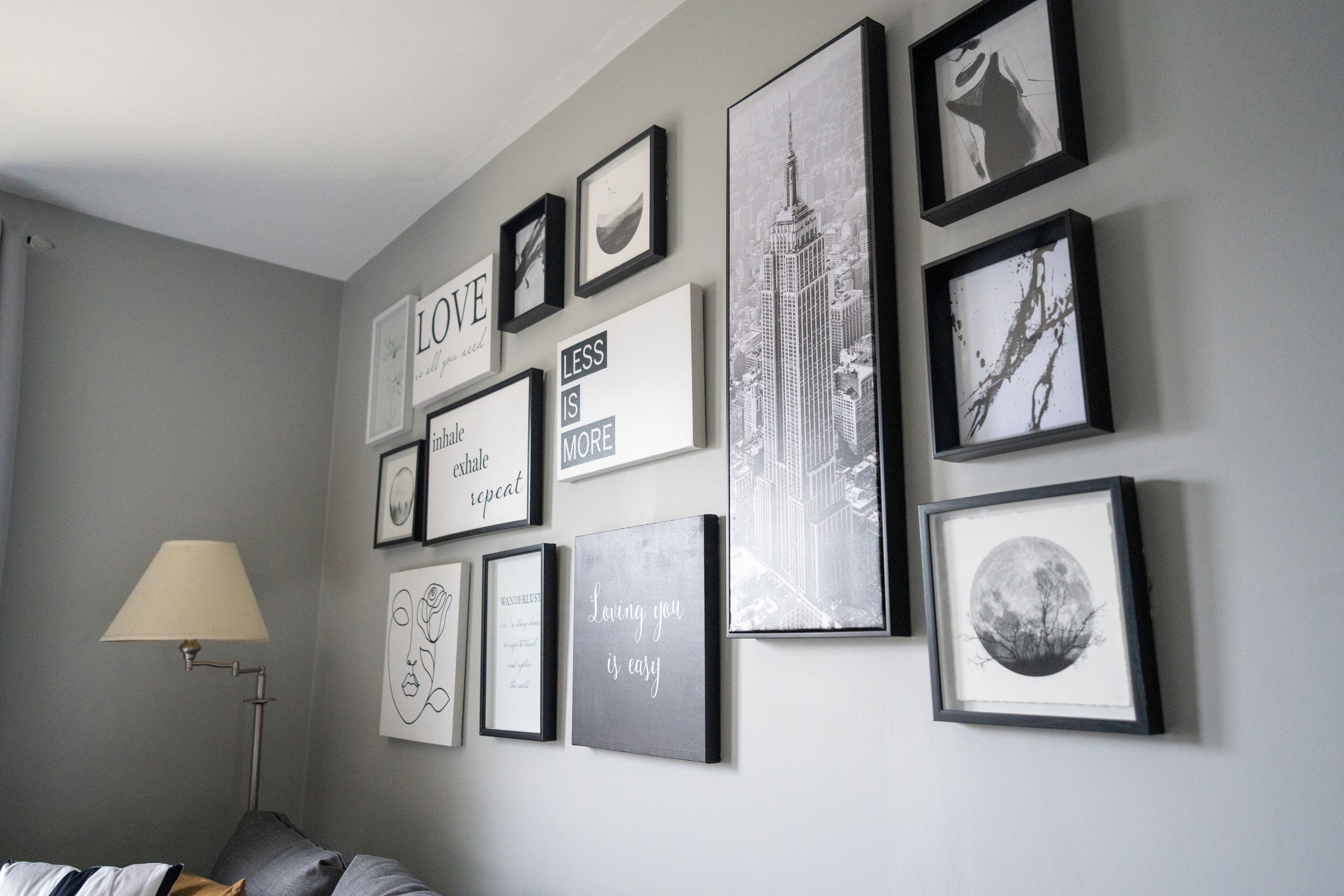A wall with various framed pictures and quotes, including a cityscape and a moon.