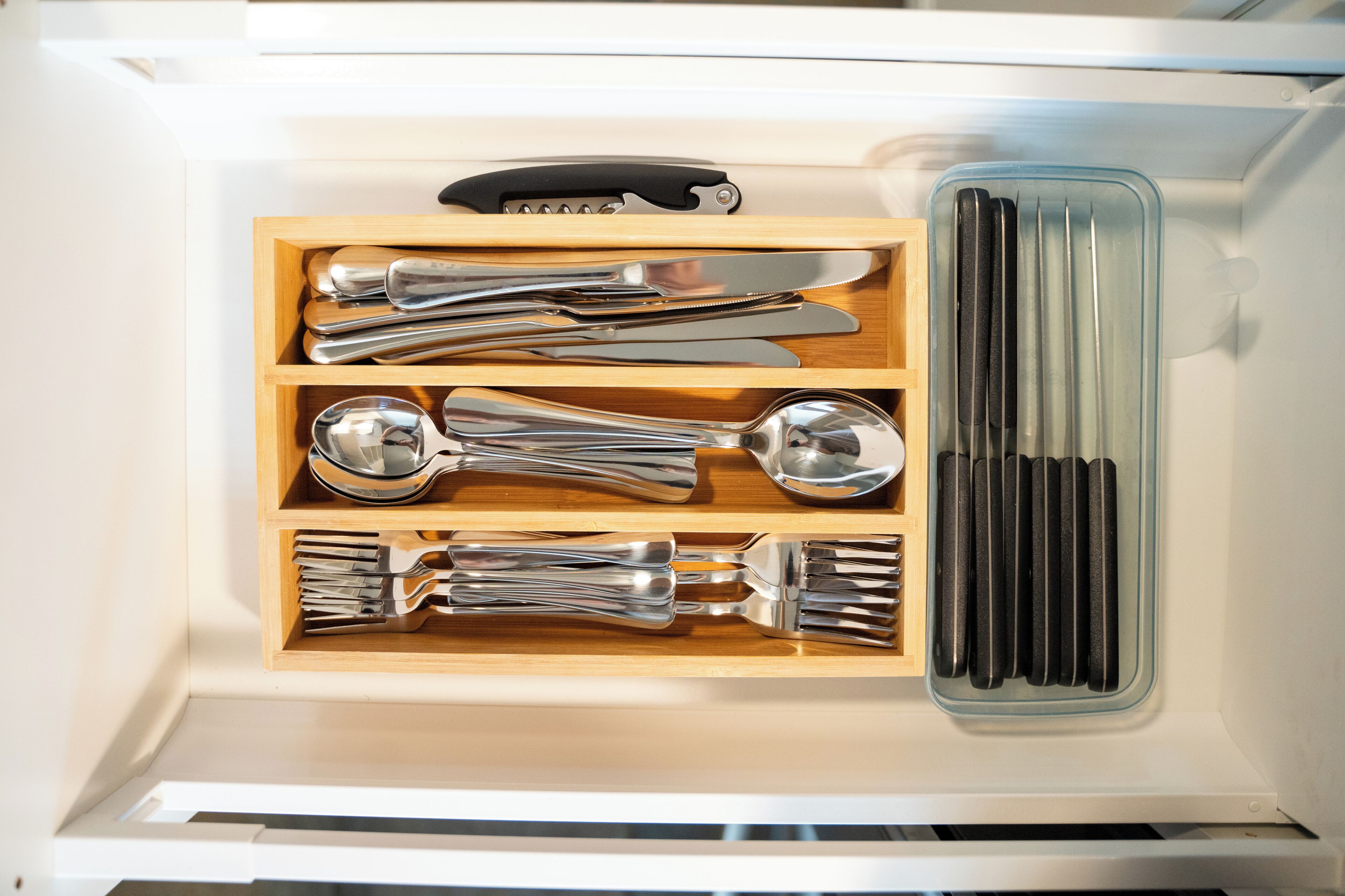 A drawer containing neatly organized kitchen utensils including forks, knives, and spoons.