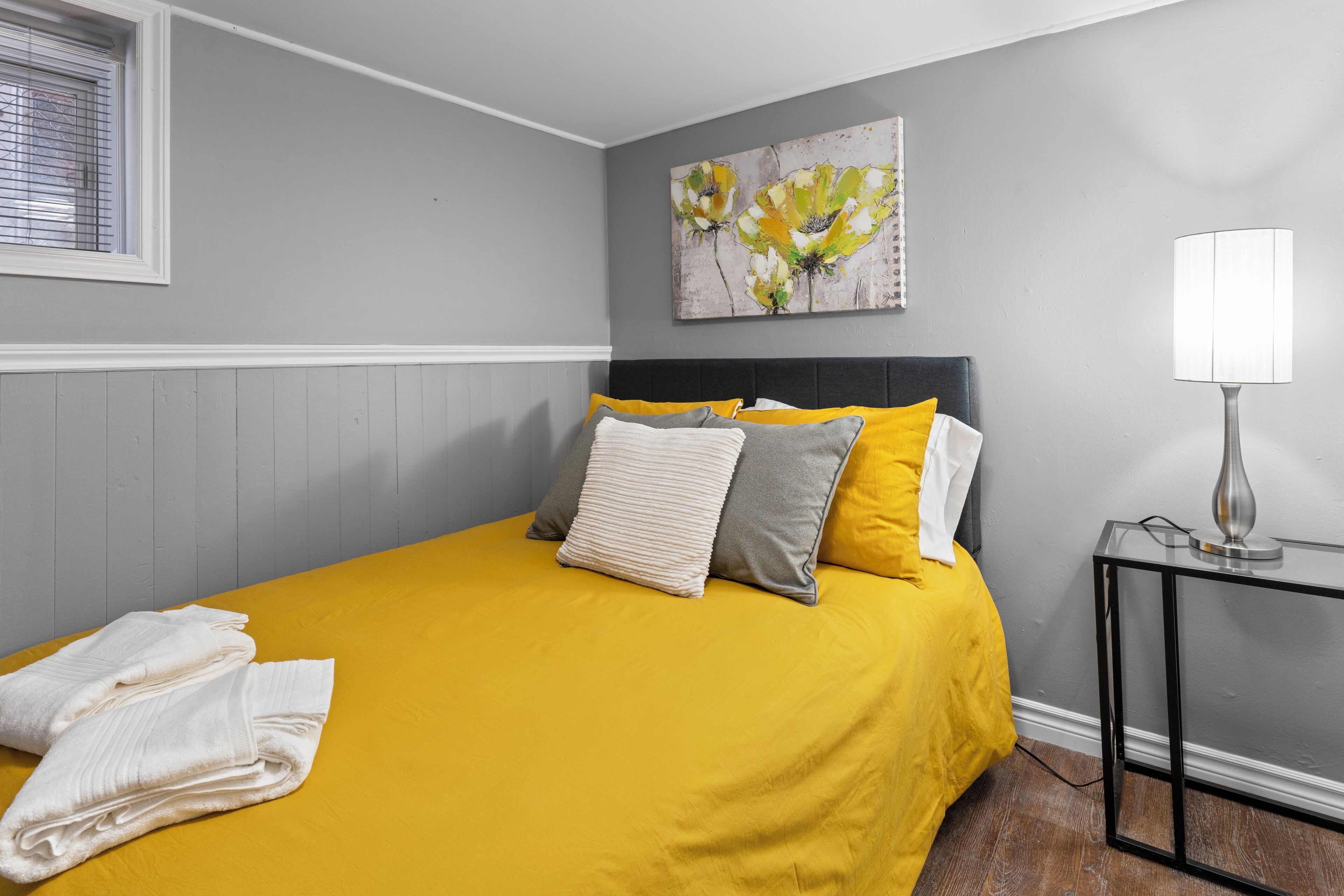 A bedroom with a bed, pillows, a bedside table, and a lamp.