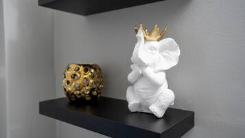 Eine weiße Elefant-Figur mit goldener Krone auf einem schwarzen Regal.