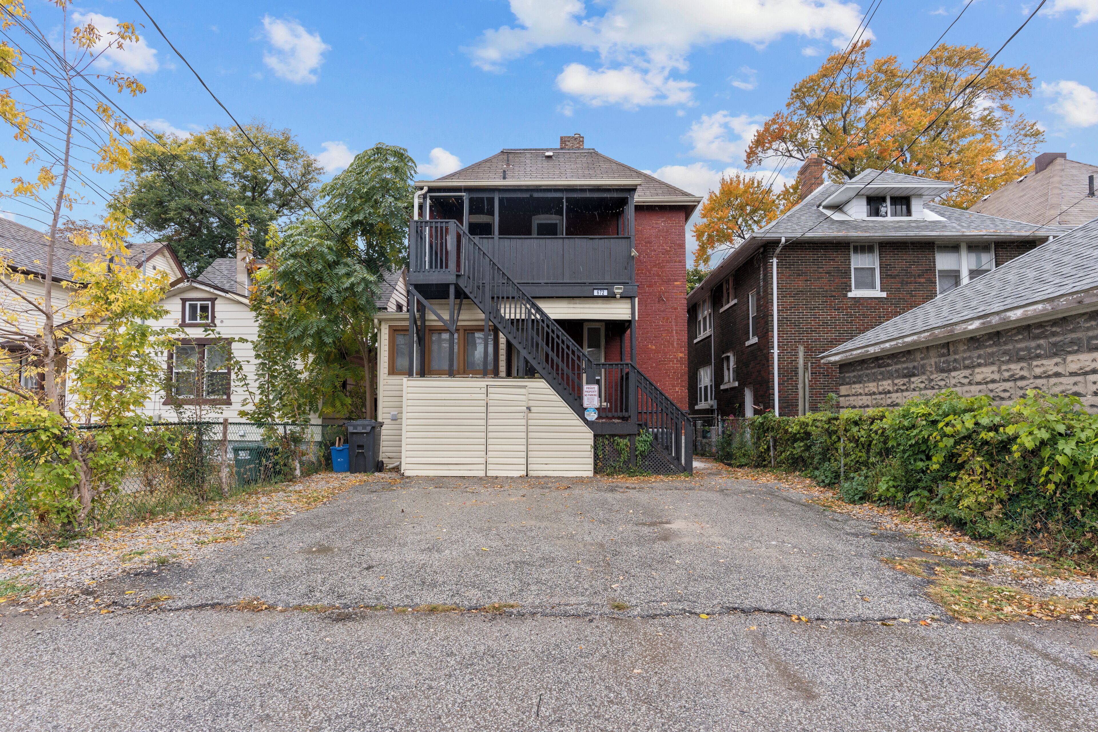 A two-story house with a front porch, a garage, and a driveway leading to the entrance.