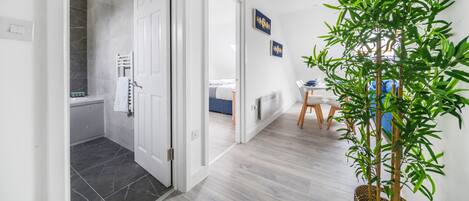 A modern hotel room with a bathroom, a dining area, and a living space.