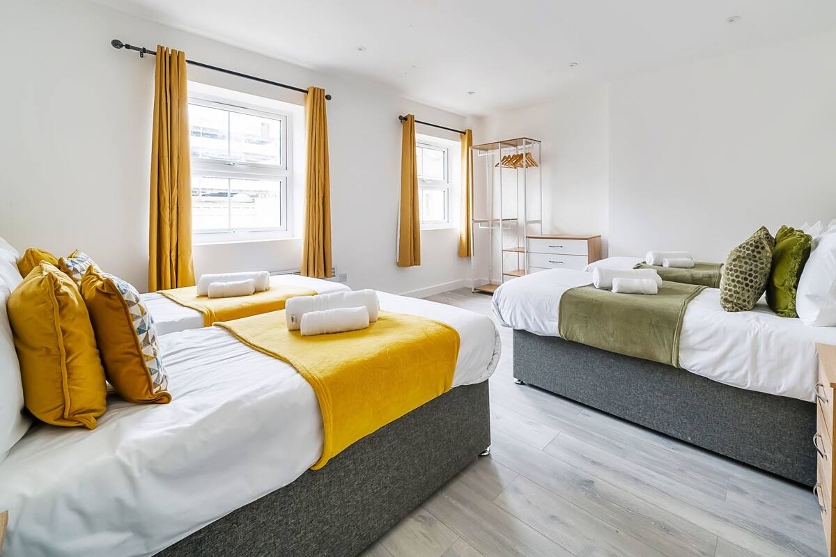 Ein Hotelzimmer mit zwei Betten, einem Holzschrank, einem Spiegel und einem Fenster mit Vorhängen.