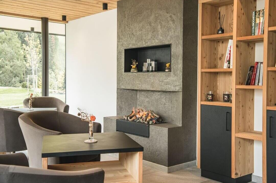 A modern living room with a fireplace, a bookshelf, and a dining area.