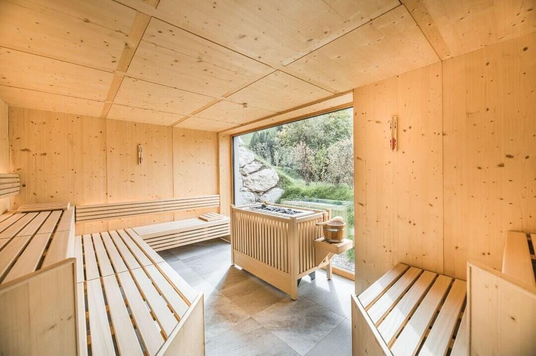 A sauna room with wooden benches and a central heating unit.