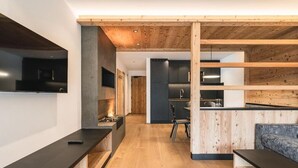 Una cocina moderna con detalles de madera, un área de comedor con un sofá y un televisor montado en la pared.