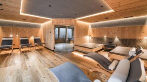 Un cuarto de spa con paredes de madera, varias camillas de masaje y una puerta de vidrio que da al exterior.