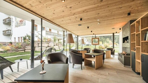 Un interior moderno con techo de madera, ventanas amplias y una variedad de zonas de estar.