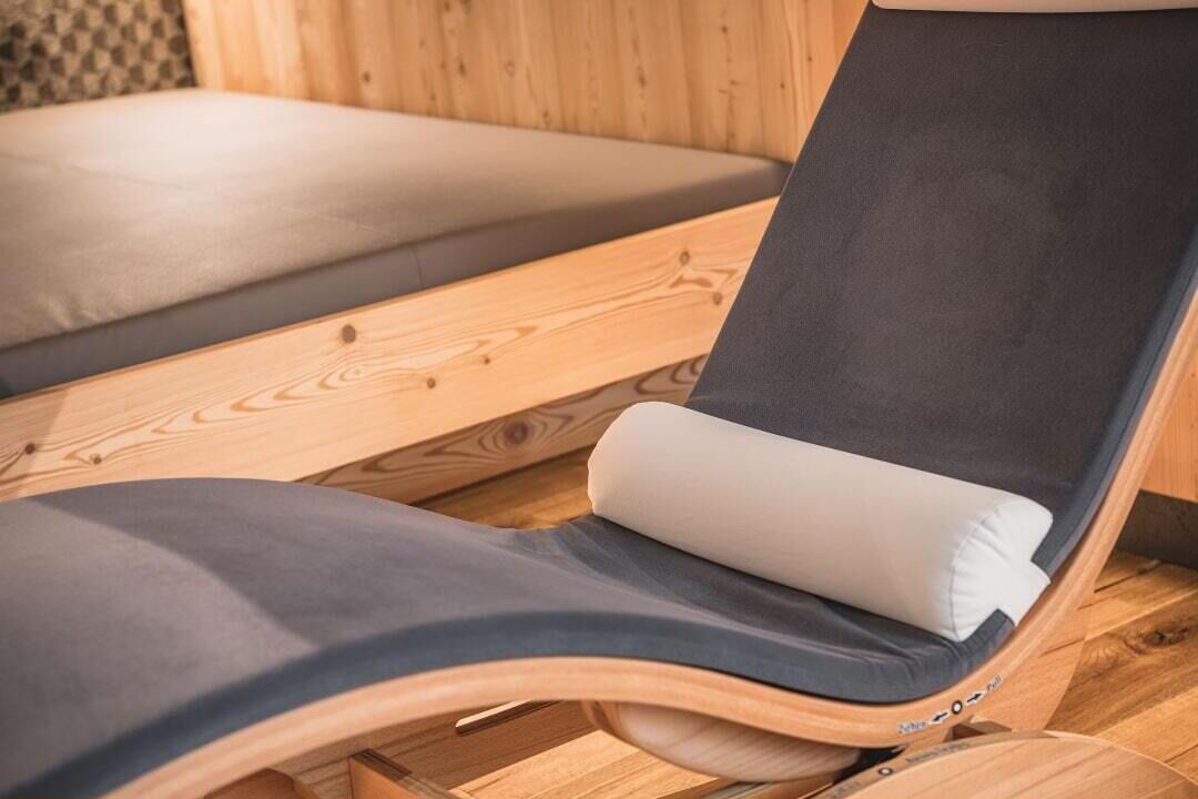 Un fauteuil de relaxation en bois, doté d’un coussin foncé et d’un oreiller blanc.