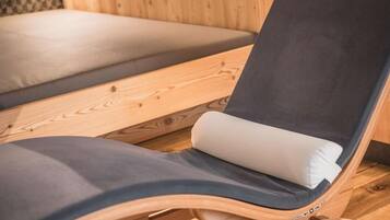 Un fauteuil de relaxation en bois, doté d’un coussin foncé et d’un oreiller blanc.