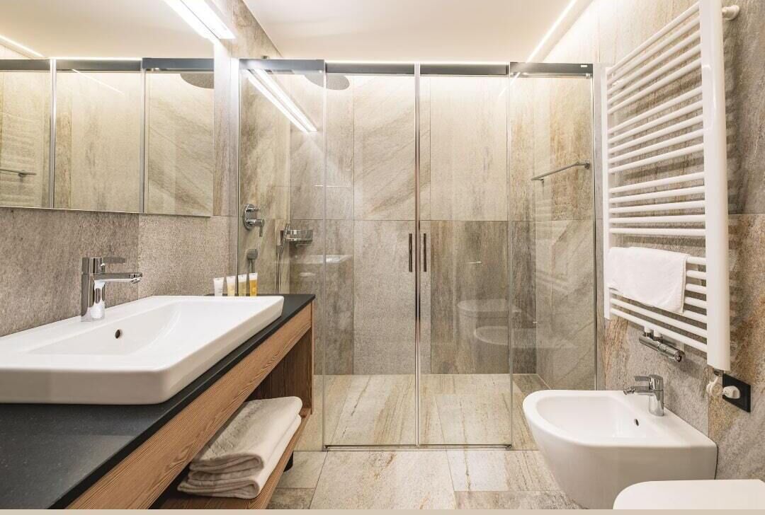 Een moderne badkamer met twee wastafels, een douchecabine en een toilet met bidetfunctie.