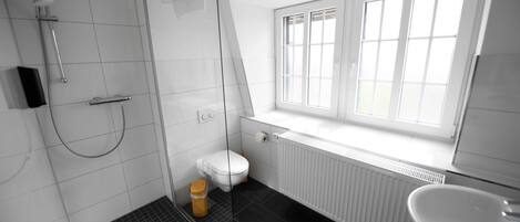 A modern bathroom with a shower, toilet, and sink.