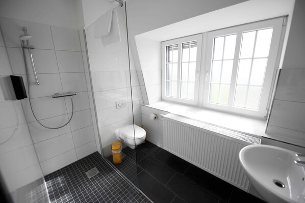 A modern bathroom with a shower, toilet, and sink. - St. Barbara-Haus (Dinslaken)